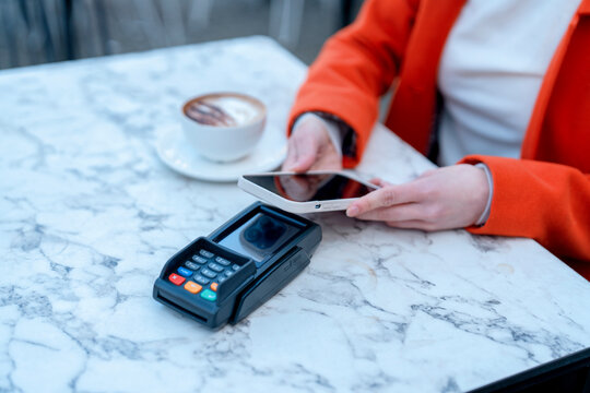Using mobile payment at a cafe with coffee on the marble table during the morning hours