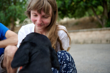 Smiling Woman Interacts with a Black Dog Outdoors in a Natural Setting