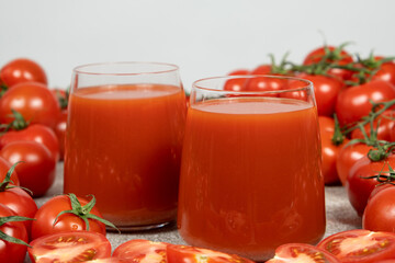 Fresh Tomato Juice in Glasses with Ripe Tomatoes Around.