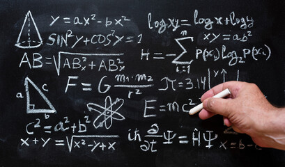 Mano escribiendo operaciones y formulas de física cuántica y matemáticas con una tiza en la...