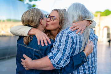 Friends share an embrace at a sunny outdoor gathering in a vibrant city park during a joyful reunion in the afternoon