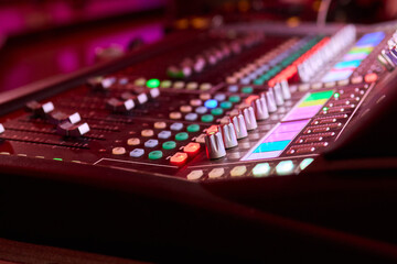 Closeup image of a hand mixing sounds on a control board, showcasing an audio technicians work
