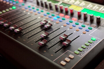 Closeup image of a hand mixing sounds on a control board, showcasing an audio technicians work