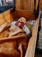 Wooden cradle with traditional doll in ethnic clothing resting inside at a cultural exhibit