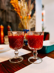 Refreshing red beverages served in decorative glasses on a wooden table with floral decor