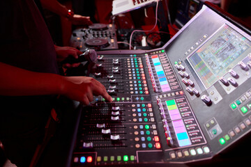 Closeup image of a hand mixing sounds on a control board, showcasing an audio technicians work