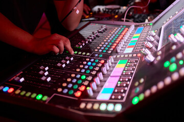 Closeup image of a hand mixing sounds on a control board, showcasing an audio technicians work