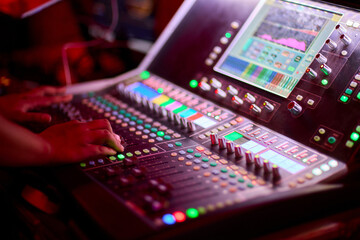 Closeup image of a hand mixing sounds on a control board, showcasing an audio technicians work