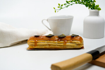 caramel glazed eclair with chocolate decors on elegant white table setting