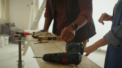 Couple planning home renovation using a drill and measurement tool - Powered by Adobe