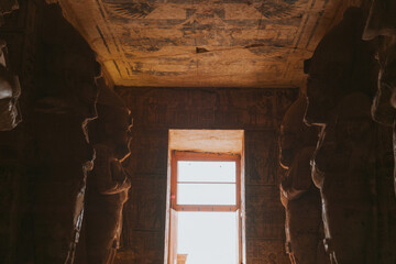 Sunlight entering egyptian temple through open window past statues