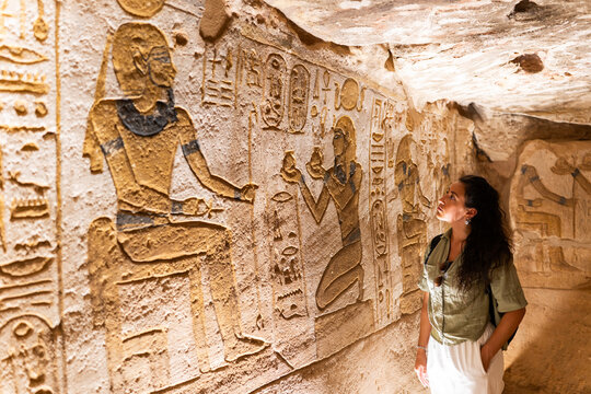 Tourist observing ancient egyptian hieroglyphics carved on a wall