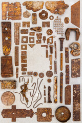 A group of various old rusty bits and pieces arranged on a concrete surface. Old rusty nuts, bolts, nails and other parts flay lay on gray background.