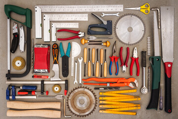 Flat lay of old hand tools on concrete background. Large collection of various rusty tools and bits arranged on concrete.