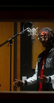 The rapper is recording a song in a recording studio. View through the window from the operator's side