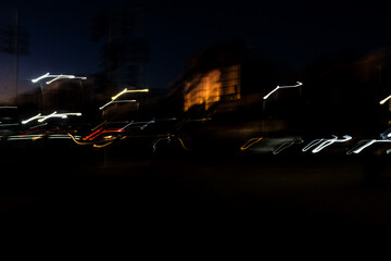 Nighttime photo of an avenue of buildings with colorful stripes. The stripes are the reflection of...