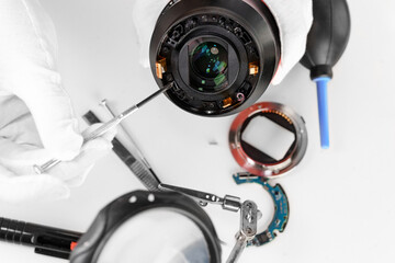 the hands of the master with gloves and a broken lens of a professional camera.