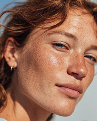 Fototapeta premium Natural beauty shines through in this close up of woman with freckles and radiant skin. Her blue eyes and soft convey confidence and warmth