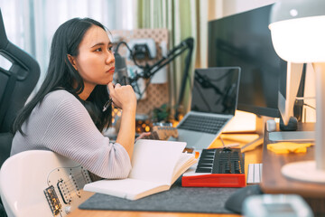 Young adult asian woman creative songwriter freelancer working composing song at music home studio