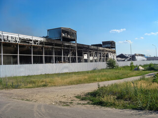 A severely damaged building with visible fire damage under a clear blue sky.