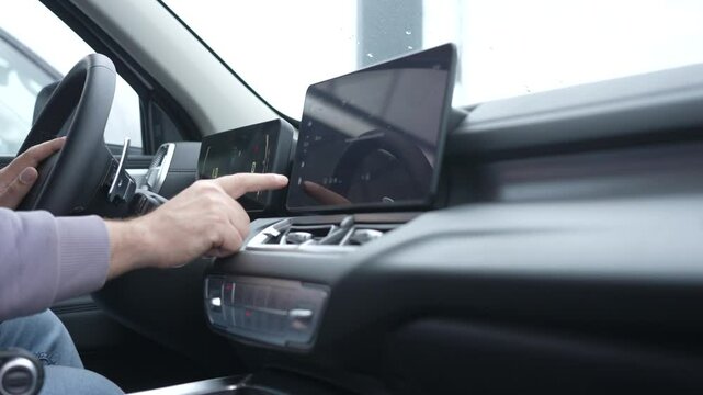A man uses a touchscreen in a modern car. 