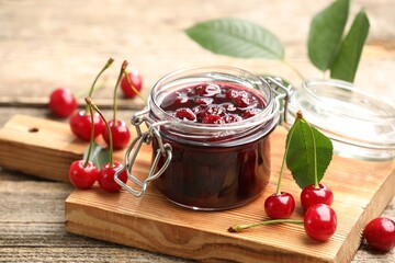 Tasty cherry jam and fresh fruits on wooden table, closeup