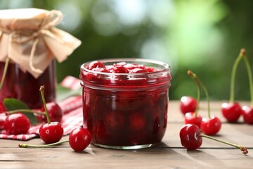 Tasty cherry jam and fresh fruits on wooden table against blurred background, closeup
