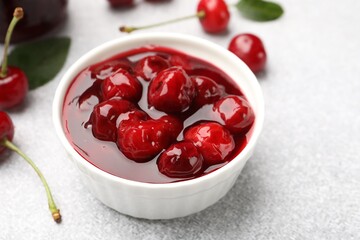 Tasty cherry jam and fresh fruits on light table, closeup