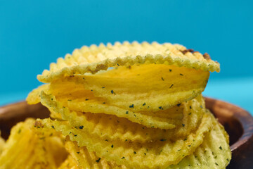 Crunchy potato chips stacked neatly with a golden hue and flecks of seasoning visible in close-up detail