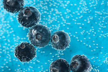 Bubbles and blueberries create a vibrant display in a refreshing drink on a bright blue surface