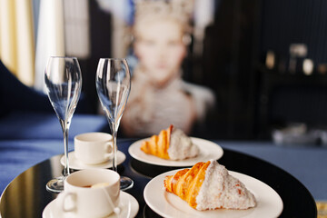 Two cups of coffee and croissants, champagne glasses on the black round table