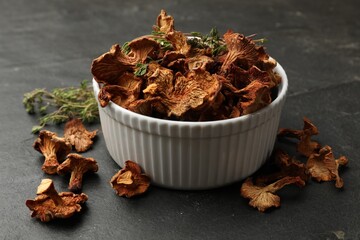 Dried chanterelle mushrooms with thyme on black table, closeup