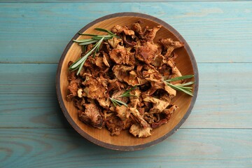Dried chanterelle mushrooms with rosemary on blue wooden table, top view