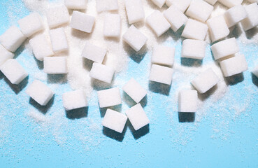 White sugar cubes on blue background top view flat lay. Scattered sugar cubes. Abstract pattern of...