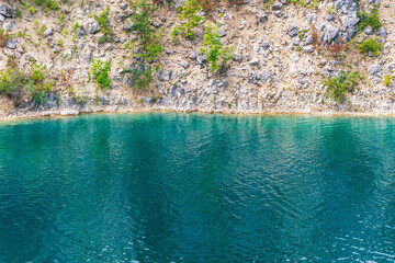 Serene emerald lake with rocky cliff and lush greenery
