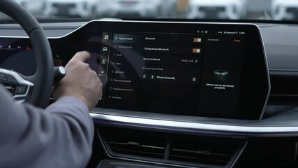 A man uses a touchscreen in a modern car.  - Powered by Adobe