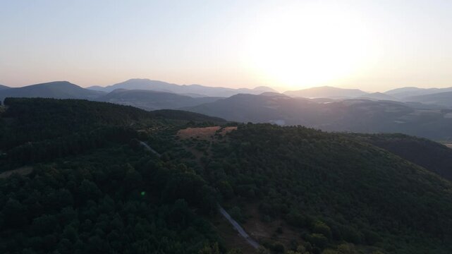 Aerial view of the Colli Folignati hills in Umbria, Italy, with sunlit fields and clear sky