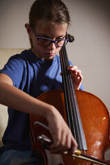 Young Girl Practicing the Cello at Home While Wearing Glasses