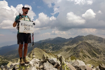 Triumphant hiker reaches Bucura Peak summit at 2433m in Retezat National Park. Mountain climber...