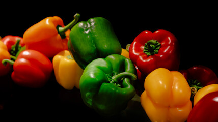 Food background, Colorful green , red and yellow bell peppers paprika isolated on black background.