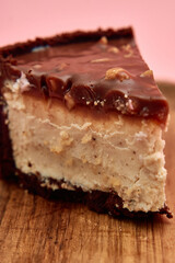 Delicious chocolate peanut butter cheesecake slice with rich ganache on wooden board