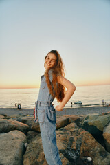 lifestyle woman in modern boho-western denim street style smiles happily outdoors by the rocky...