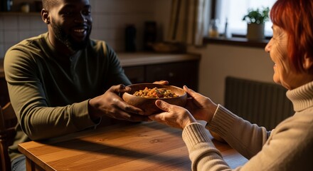Man smiling while handing bowl of food to elderly woman at home  