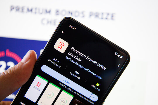 A lifestyle image featuring the Premium Bond Prize Checker app displayed on a mobile phone held in a hand