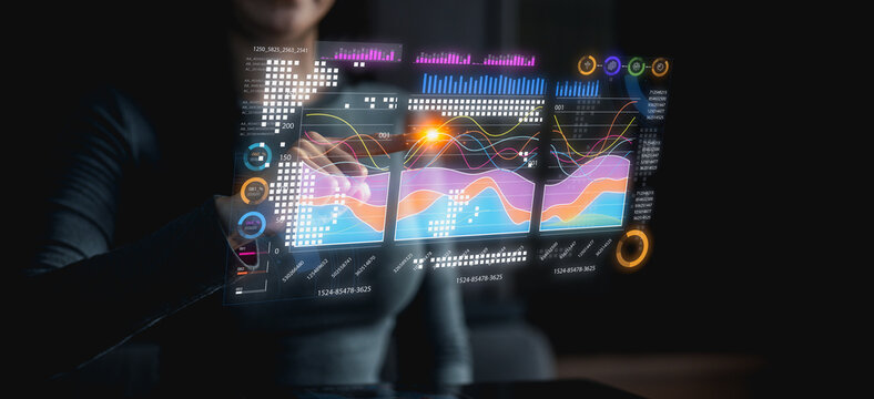 A person interacts with a futuristic transparent digital interface displaying colorful data charts and analytics in a dark environment.