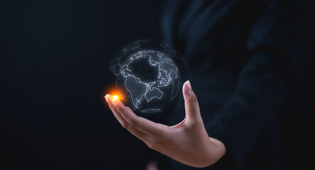 A hand holds a glowing digital globe, symbolizing global connection and technology in a dark, futuristic setting.