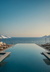 Fototapeta premium Infinity pool with lounge chairs and umbrellas facing the ocean