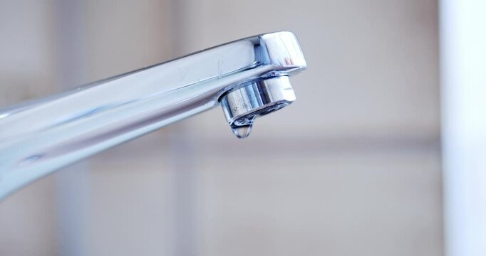 Dripping tap with water droplets inside apartment bathroom. Macro, close up, looking up shot, shallow depth of field, real time, no people