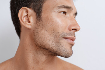 Fototapeta premium Close up of man with enlarged pores and uneven skin texture showing natural facial hair and smooth skin tone, expressing calm and confidence in neutral background