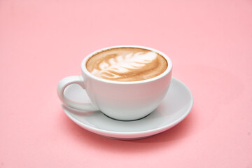 Elegant latte art in white ceramic cup on soft pink background